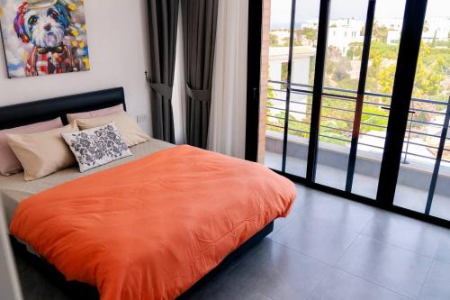 a bedroom with an orange bed and a large window at Kensington Villa - Private Pool & Rooftop Terrace by Azur Prime in Ayios Yeoryios