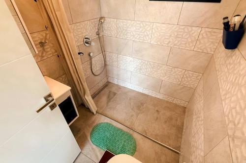 a small bathroom with a shower and a green stool at Kensington Villa - Private Pool & Rooftop Terrace by Azur Prime in Ayios Yeoryios