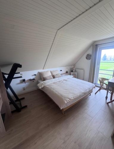 a bedroom with a large bed and a large window at Charmante maison rénovée in Fernelmont
