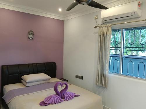 a bedroom with a bed with purple towels on it at OCEAN LODGE in Pantai Cenang
