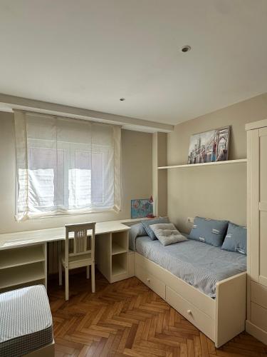a bedroom with a bed and a desk and a window at Xanela da Ría in Quenje