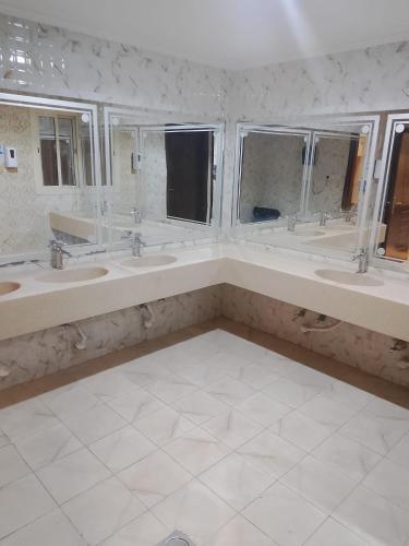 a bathroom with three sinks and three windows at فندق بلورة البشاير in An Naqāʼ
