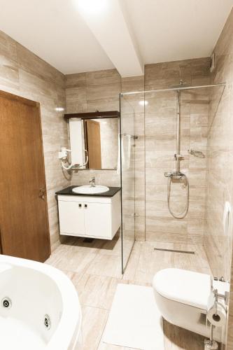 a bathroom with a tub and a sink and a shower at Hotel Centrum Prizren in Prizren