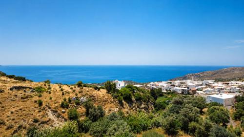 a village on a hill with the ocean in the background at Aethra Seaview Suites in Kerames