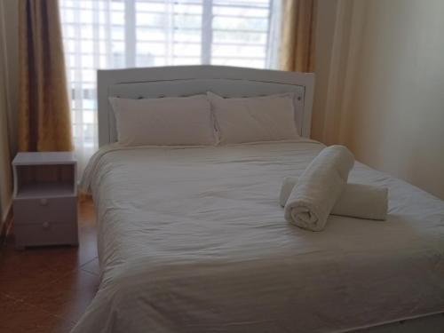 a white bed with two towels on top of it at EMIC Suites in Nyahururu