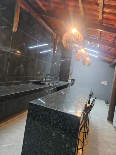 a kitchen with a black counter and some lights at Recanto JF in Pirapora