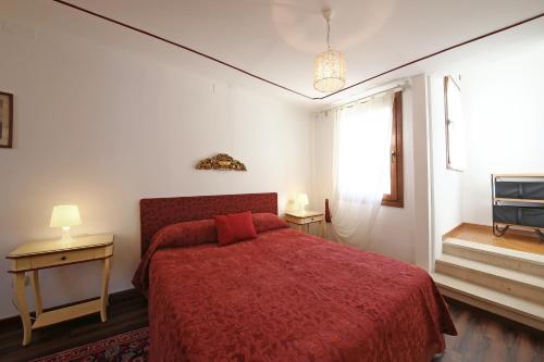 a bedroom with a red bed and a window at Appartamenti inside Palazzo Foscarini in Venice