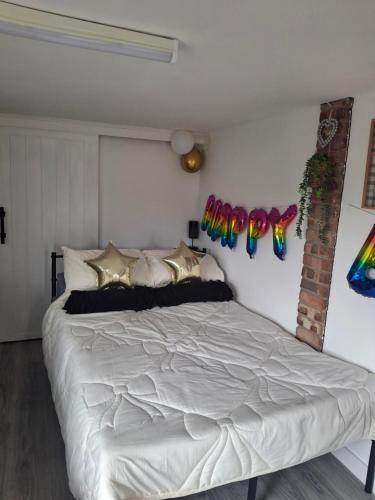 a bedroom with a large white bed with decorations on the wall at Nett'Als Lodge Studio Apartment in Derby