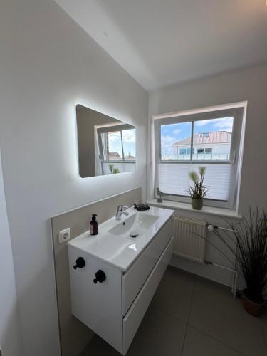 a white bathroom with a sink and a mirror at Möwennest 13 Scharbeutz in Scharbeutz