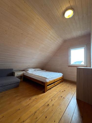 a bedroom with a bed and a couch in a room at Domki Nadmorska Oaza nad morzem i jeziorem in Jezierzany