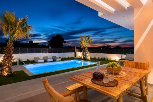 a patio with a table and a swimming pool at Martini Villas in Kremasti