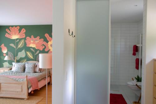 a bedroom with a bed with pink flowers on the wall at L'Effet Papillon - Maison d'hôtes in Sauges