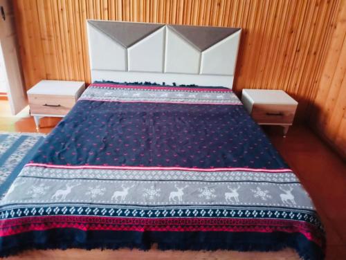 a bedroom with a large bed with a blue blanket at Ushba Hearth House in Tvebishi