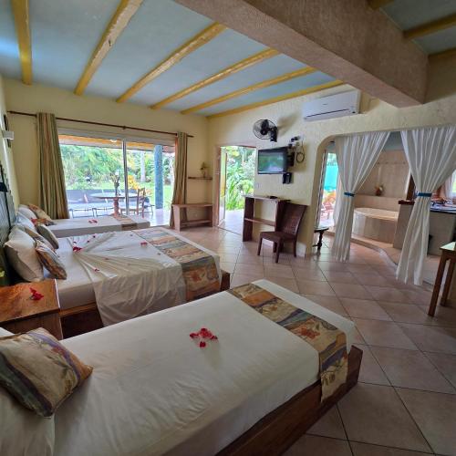 a bedroom with two beds and a living room at La Diguoise in La Digue