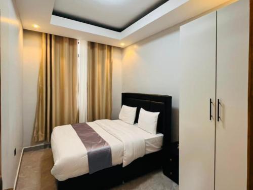 a bedroom with a bed with white sheets and pillows at Appartements Rebero Hills in Kigali