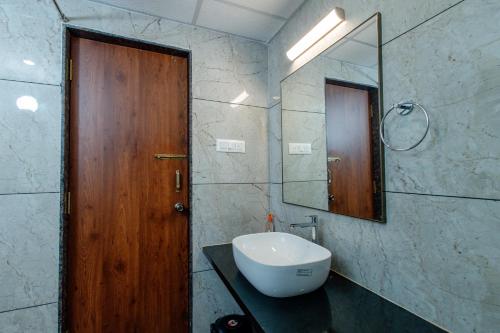 a bathroom with a sink and a wooden door at Sunlit Shores Beach Villa in Kundapur