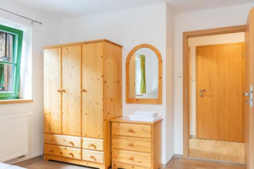 a bedroom with a wooden cabinet and a mirror at Chata Rozhlas in Železná Ruda
