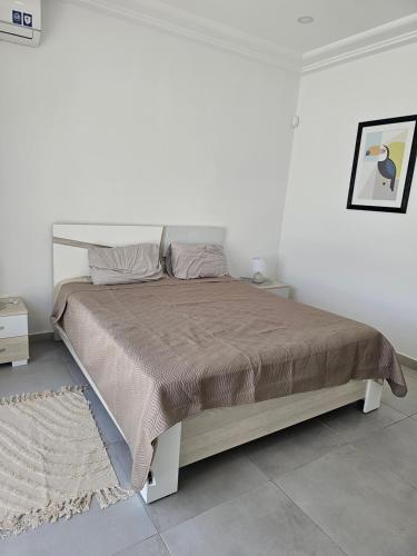 a bed in a white room with a large bed at Villa Wissal Djerba piscine privée in Arkou