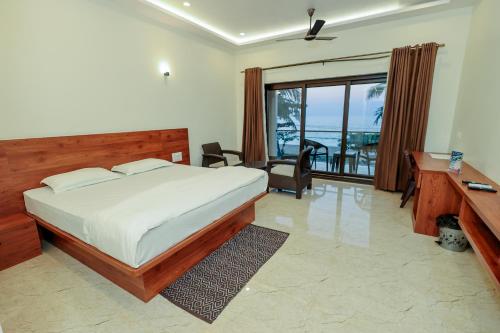 a bedroom with a bed and a desk and a balcony at Sunlit Shores Beach Villa in Kundapur