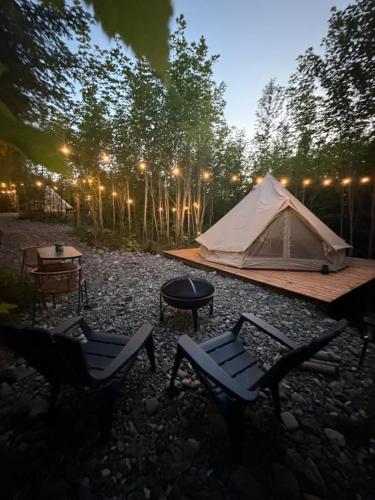 a tent and two chairs and a table and a table at Mytik Shack Sucré in Saint-René-de-Matane