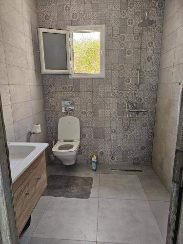 a bathroom with a toilet and a tv on the wall at Villa Wissal Djerba piscine privée in Arkou