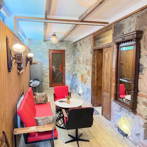 a room with red chairs and a table and a stone wall at HALI Guest Hause in Dilijan