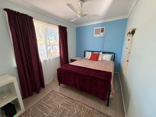 a bedroom with a bed with blue walls and a window at Opal St Homestay in Lightning Ridge