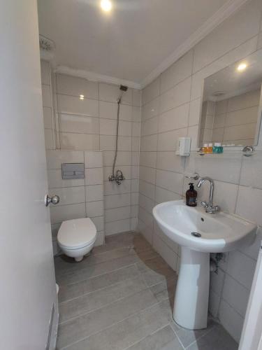 a white bathroom with a toilet and a sink at dolunaydın hotel in Side