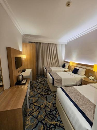 a hotel room with two beds and a television at Al Madina Golden Hotel in Medina