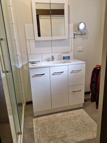 a white bathroom with a sink and a mirror at Private Studio Ensuite & Kitchenette in Glen Waverley