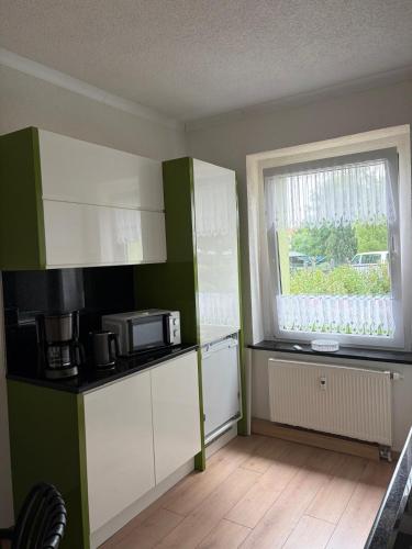 a kitchen with green and white cabinets and a window at Apartments Zur Eiche in Großräschen