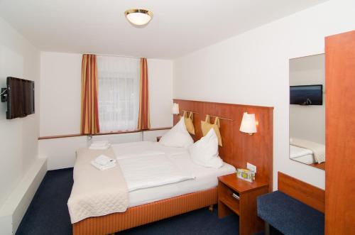 a hotel room with a bed and a mirror at Hotel -Restaurant Taormina in Birkenfeld