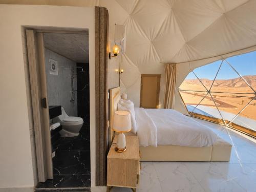 a bedroom with a bed and a view of the desert at Wadi Rum Luxury Hamad & Jeep Tours in Wadi Rum
