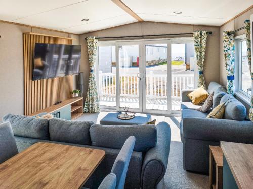 a living room with blue couches and a tv at Peachy in Heysham