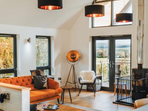 a living room with an orange couch and windows at Strathspey Lodge in Duthil