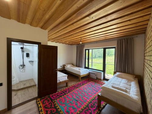 a room with two beds and a shower and a rug at Kordon guest house in Tar-Suu