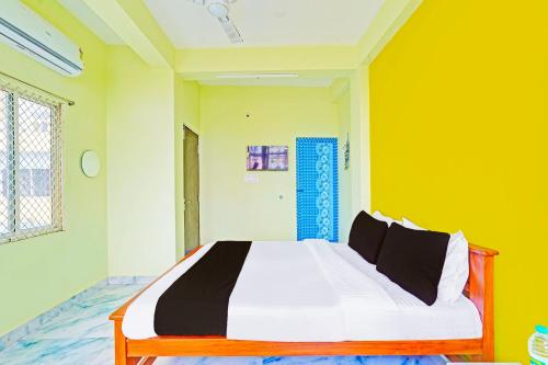 a bedroom with a large bed in a yellow wall at Hotel O by OYO LA VGA RESIDENCY in Kottakupam