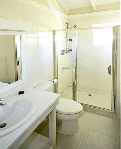 a white bathroom with a toilet and a shower at Mango Court 1 - by ZenBreak in Saint James