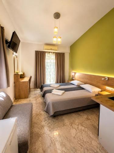 ein Schlafzimmer mit drei Betten und einer grünen Wand in der Unterkunft Hotel Marti Studios in Skala Sotiros