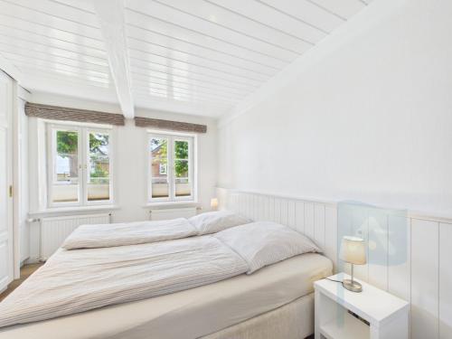 a white bedroom with a bed and two windows at Min aran in Oevenum