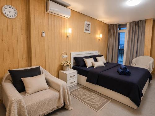 a bedroom with a bed and a chair and a clock at Trio Villas Retreat in Grigoleti