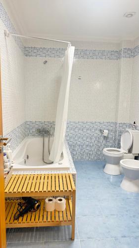 a blue and white bathroom with a tub and a toilet at Casa Lua Guesthouse in Burgau