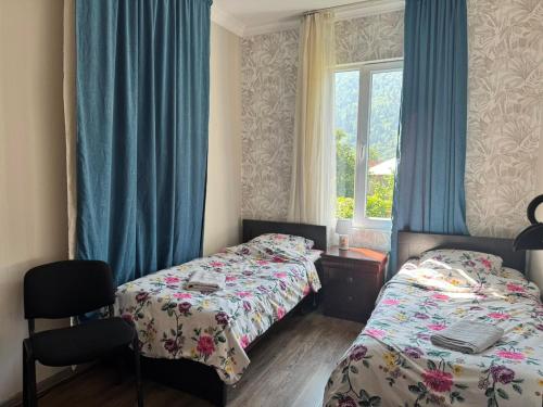 a bedroom with two beds and a window with blue curtains at Svaneti Heaven in Lentekhi