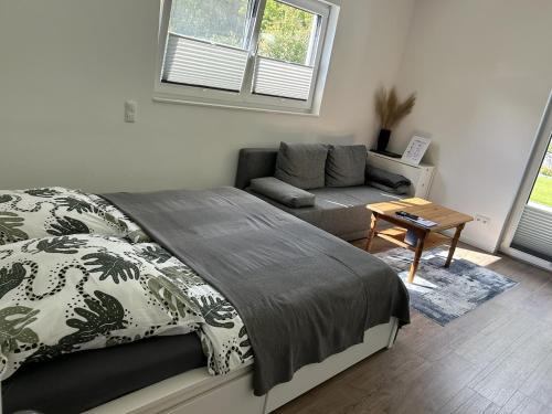 a bedroom with a bed and a couch and a table at Moderne 1-Zimmer-Gästewohnung im Neubau mit schönem Garten in Pronstorf