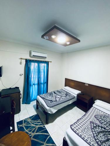 a room with two beds in it with blue curtains at فندق الليدو in Marsa Matruh