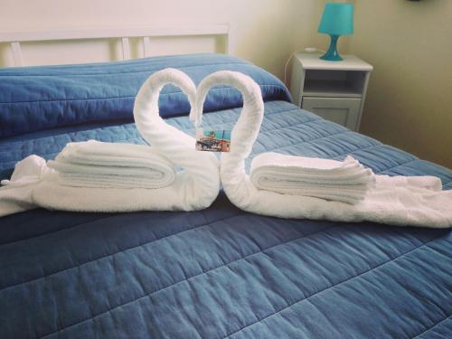 two towels shaped like swans sitting on a bed at Blue Eden Strait in Messina