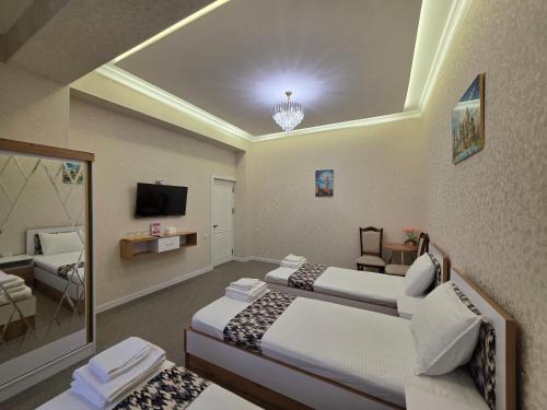 a hotel room with two beds and a television at Bekh House SAM in Samarkand