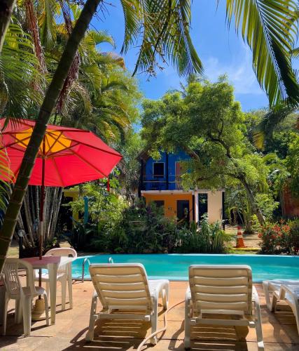 a pool with chairs and umbrellas next to a pool at Cajibá Imbassai in Imbassai