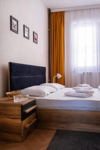a bedroom with a bed with a table and a window at UrApartment in Prizren
