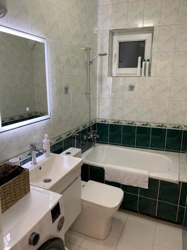 a bathroom with a tub and a toilet and a sink at UrApartment in Prizren